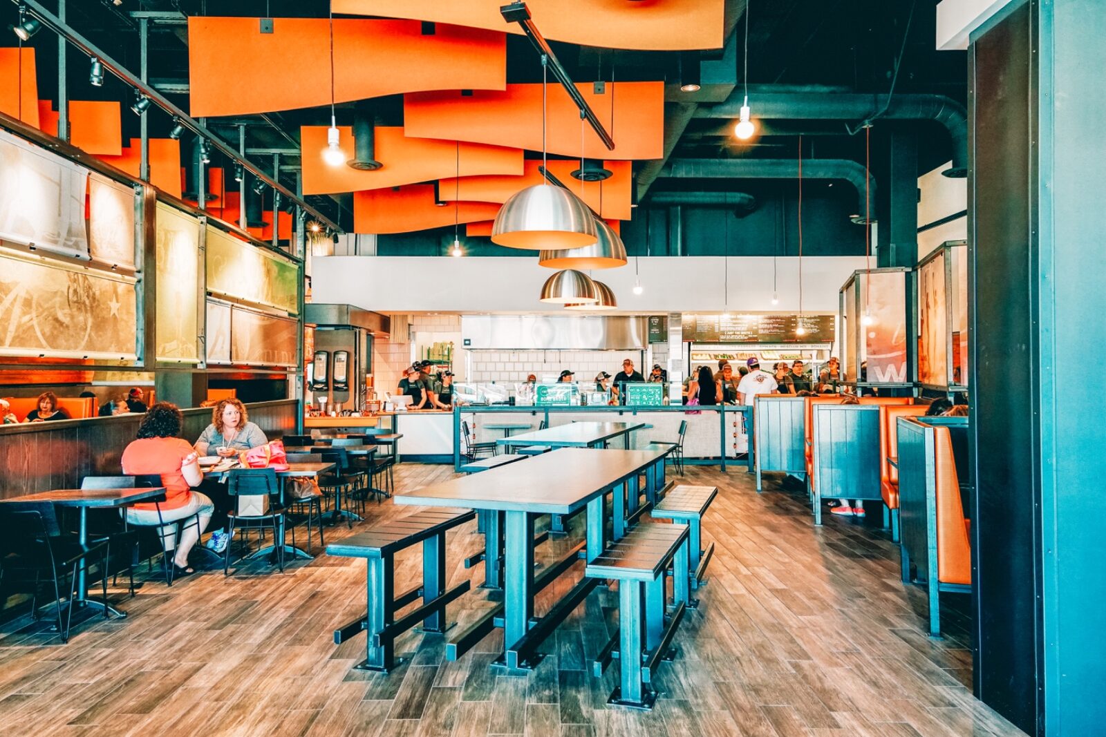 CoreLife Eatery dining room with wood tables, greenery and warm pendant lighting