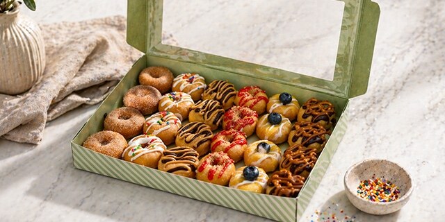 A 24-count box of decorated mini doughnuts prepared for catering