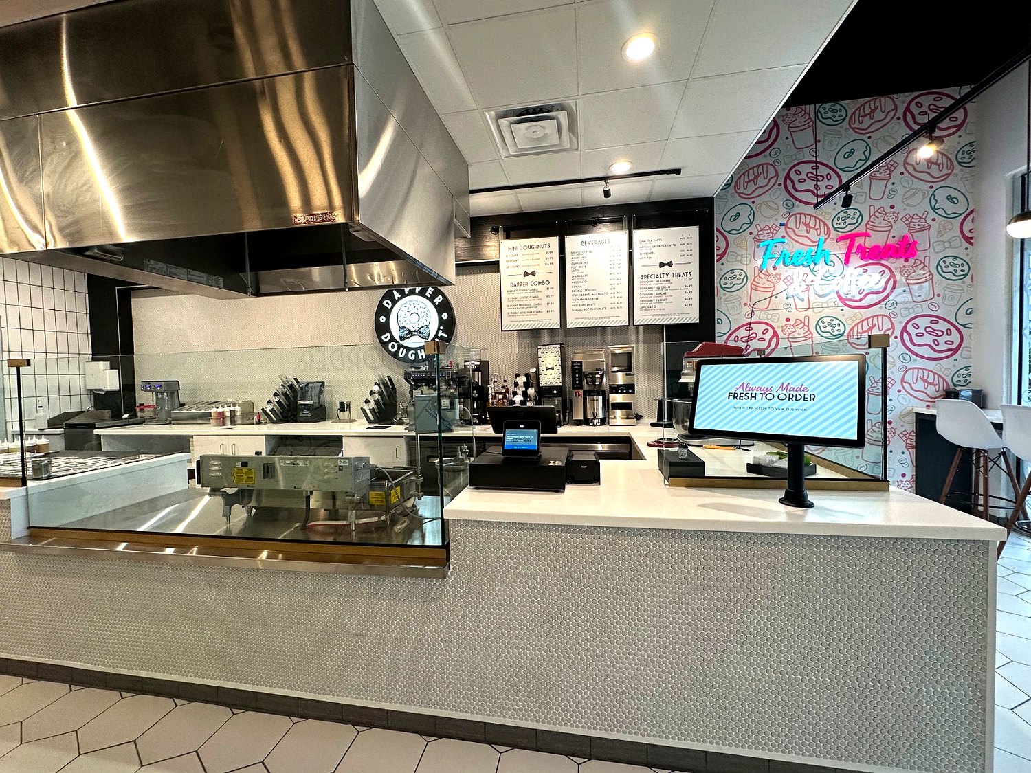 Dapper Doughnut service counter with menu boards, the round logo and the Fresh Treats and Coffee neon wall